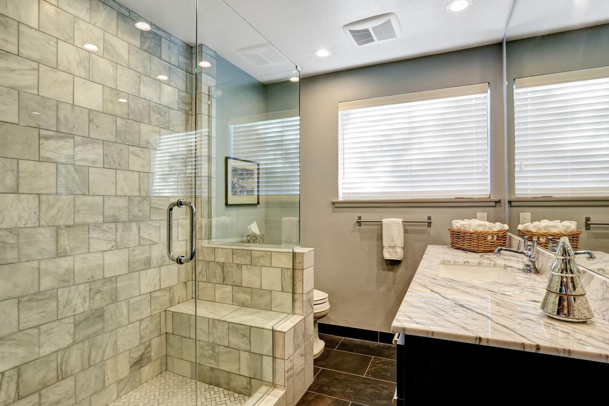 Contemporary bathroom remodel with marble tiles and glass shower enclosure by Crosby Home Services in Prescott, AZ