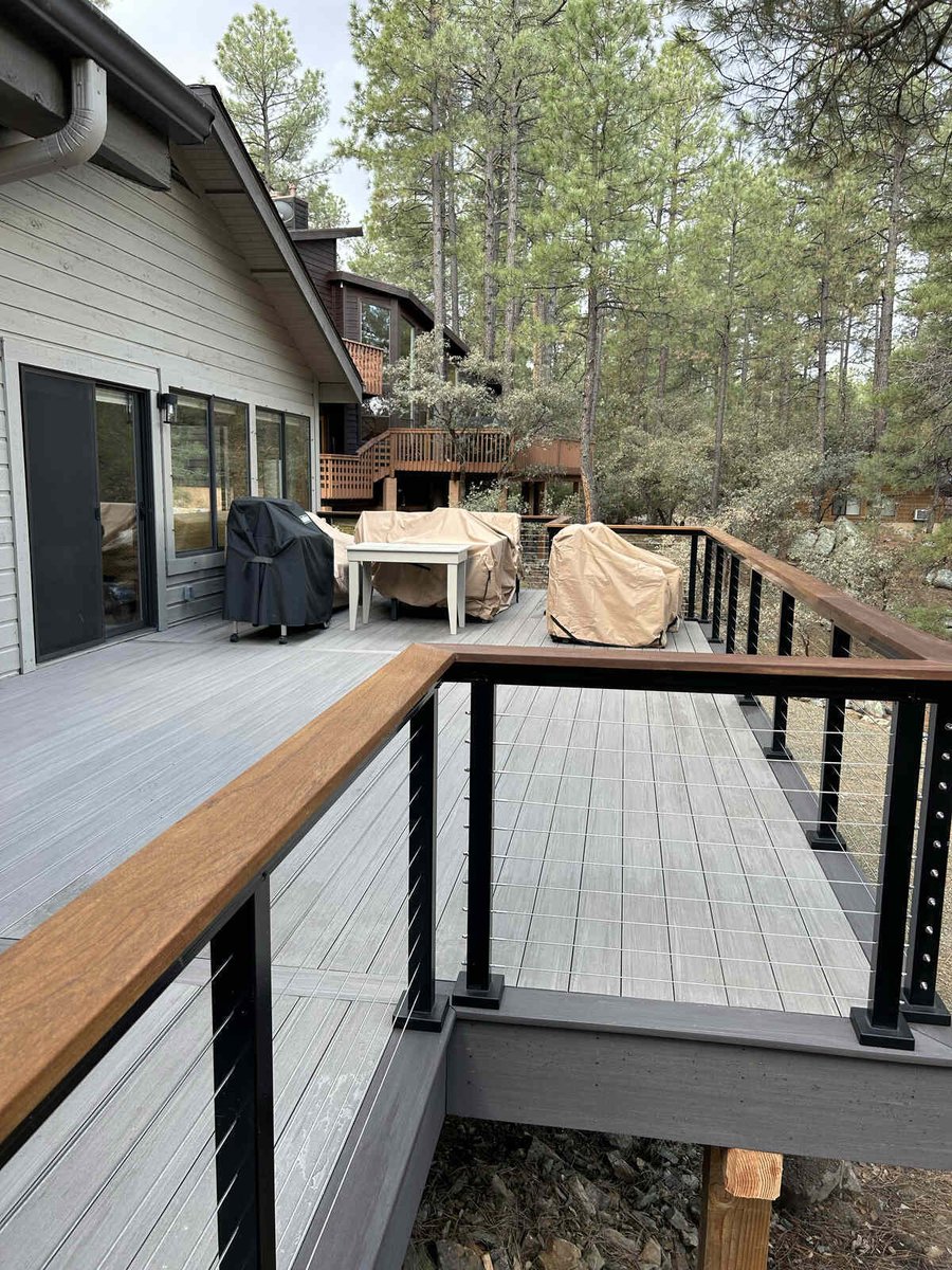 A contemporary deck with cable railing and a view of a forest, completed by Crosby Home Services in Prescott, AZ