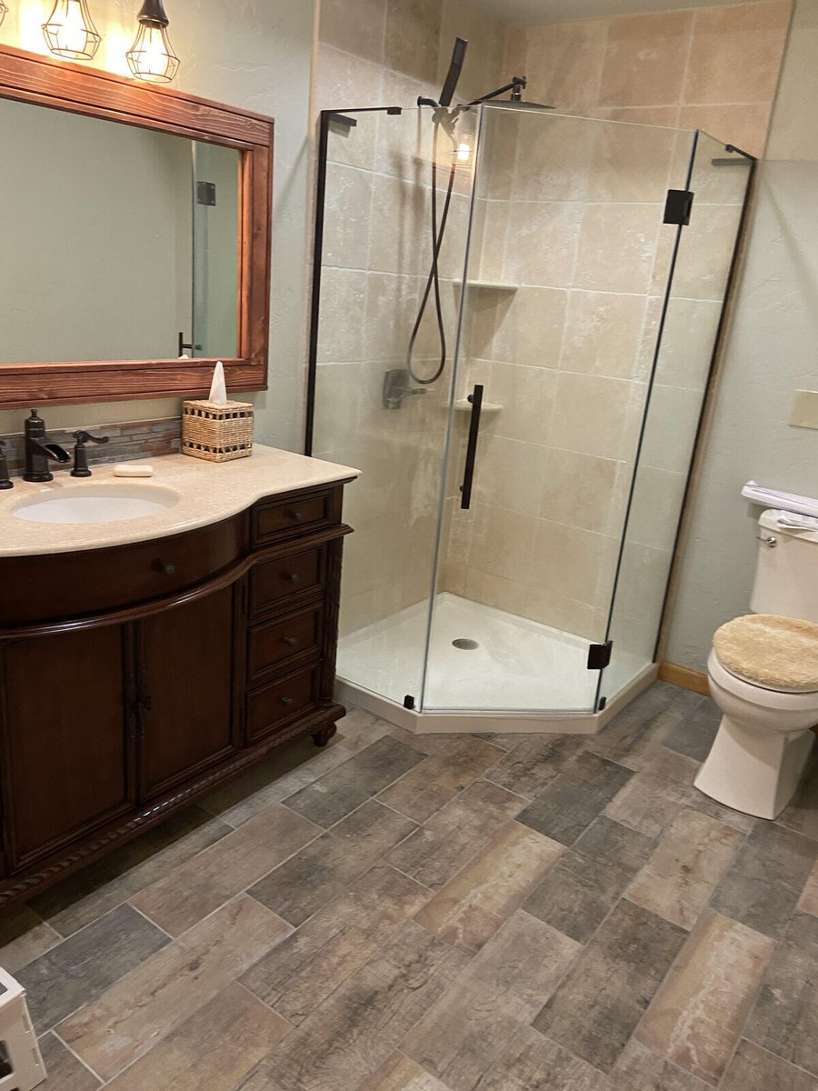 A remodeled bathroom with a glass-enclosed shower and wooden vanity by Crosby Home Services in Prescott, AZ